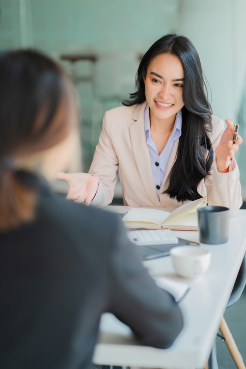 Two Asian business women working together using digital tablets discussing new startup project ideas. Analyze the planning and statistics of the financial and investment markets at the office.